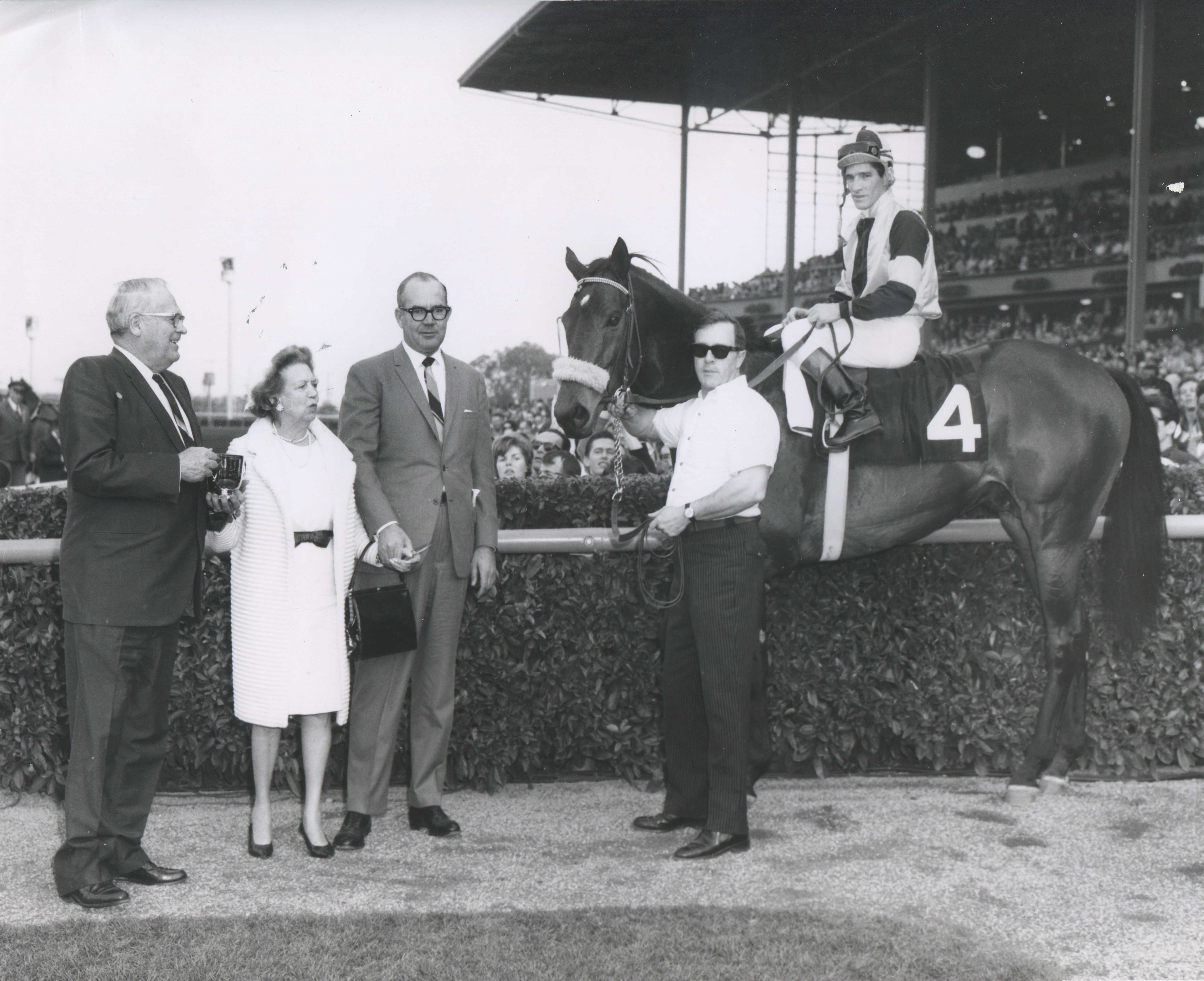 Gun Bow (Manuel Ycaza up) in the winner's circle for the 1965 San Antonio Handicap with trainer Eddie Neloy and owner Elizabeth Arden Graham (Santa Anita Photo/Museum Collection)