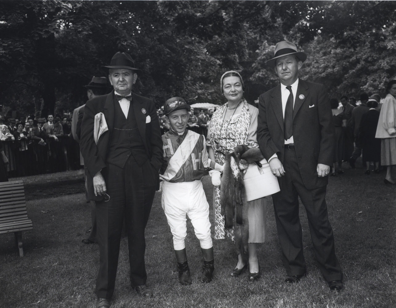 John Adams with owners Mr. and Mrs. A. E. Reuben and trainer Harry Trotsek (far right) in the Belmont Park paddock, May 1954 (Keeneland Library Morgan Collection/Museum Collection)