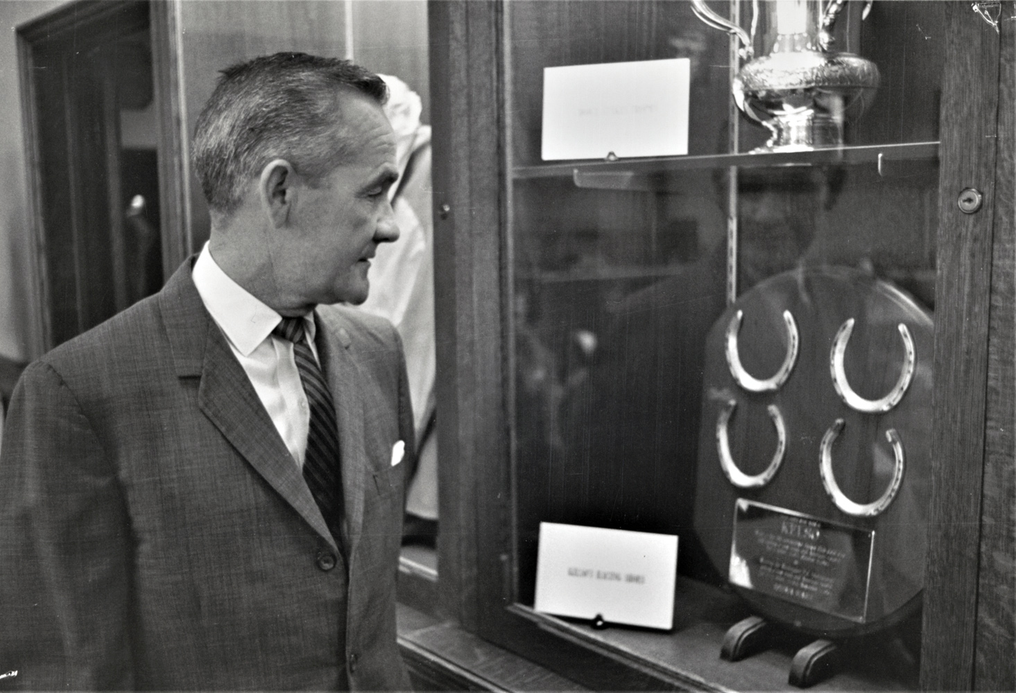 Carl Hanford looks at a display of Kelso's horseshoes and trophies (Keeneland Library Thoroughbred Times Collection)